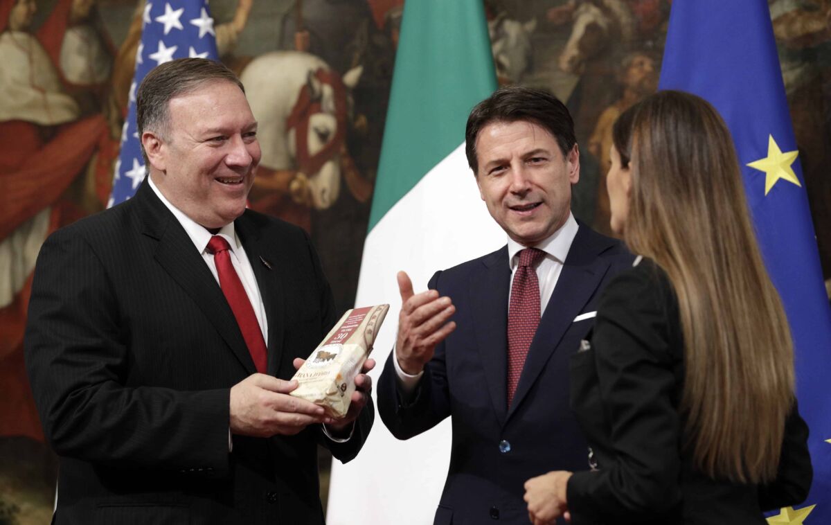 U.S. Secretary of State, Mike Pompeo, left, holds a package of parmesan cheese he was given by a journalist as Italian Premier Giuseppe Conte stands beside him, following their meeting at Chigi Palace premier's office in Rome, Tuesday, Oct. 1, 2019. 2019. U.S. Secretary of State Mike Pompeo is in Italy at the start of a four-nation tour of Europe as the push to impeach President Donald Trump gains steam at home. (AP Photo/Andrew Medichini)