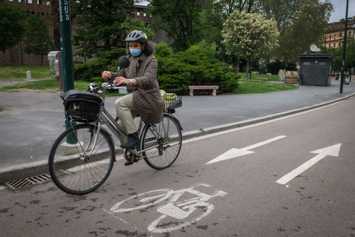 Un ciclita con il volto coperto da una mascherina percorre in bicicletta la pista ciclabile in piazza Castello, 21 aprile 2020. Per favorire l'uso della bici in sicurezza, evitare laffollamento sui mezzi pubblici e disincentivare l'uso dell'autoil ilcomune di Milano stà considerando  lampliamento della rete delle piste ciclabili a Milano in vista della fase di riapertura dopo il lockdown per  lemergenza epidemia coronavirus Covid-19. Milano 21 Aprile 2020. Ansa/Matteo Corner