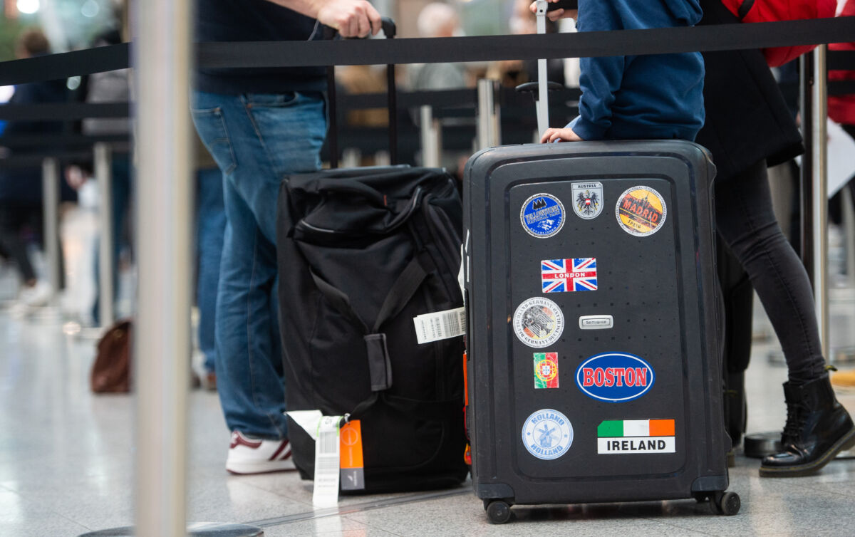 21 December 2020, North Rhine-Westphalia, Duesseldorf: A family queues with their luggage at the airport for a Corona test, while a British flag with the words "London" can be seen on the suitcase. Due to the emergence of a new, supposedly more contagious variant of the virus in the south-east of England, flights from the UK have been grounded as of today, although flights to the UK are continuing. Photo: Jonas Güttler/dpa