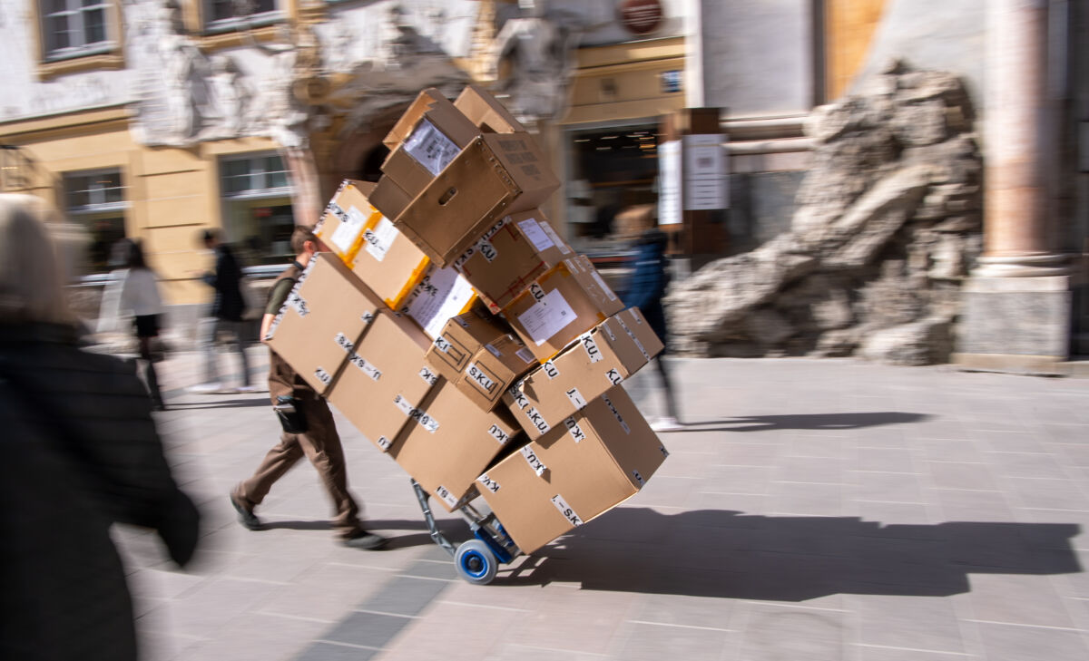 25 March 2021, Bavaria, Munich: A parcel delivery man transports several parcels with a hand truck through a pedestrian zone in the city centre. Photo: Peter Kneffel/dpa