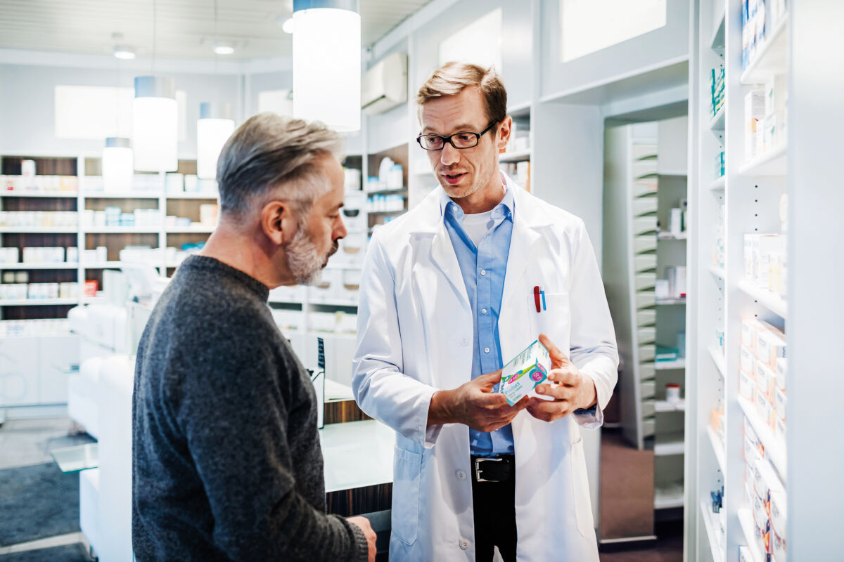 A pharmacist advising a customer on instructions concerning how to take the prescription medicine.