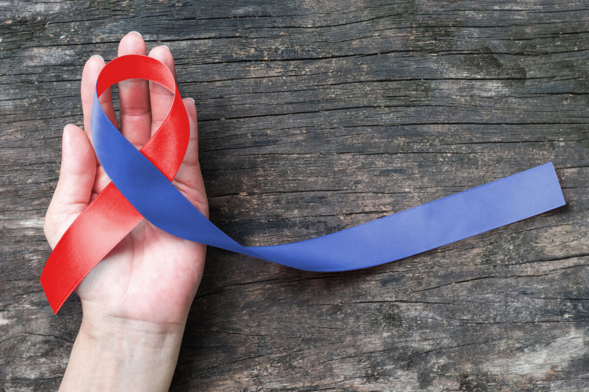 Red,Blue,Ribbon,Awareness,On,Woman's,Hand,And,Aged,Background
