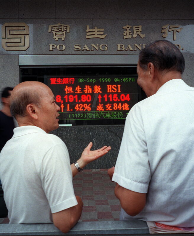 E26-19980908-HONGKONG (CINA): Two local men talk on the street in front of an electronic sign displaying the closing price of the key Hang Seng Index 08 Sept. Share prices again rose today 1.4 percent to a six week high of 8,189.25 after the Hong Kong government today called for a global plan to fight speculators.  PETER PARKS/ANSA/TO