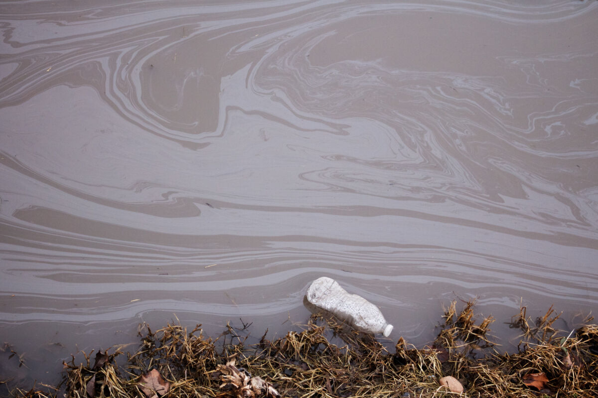 A,Discarded,Water,Bottle,Floats,In,A,Polluted,Stream.