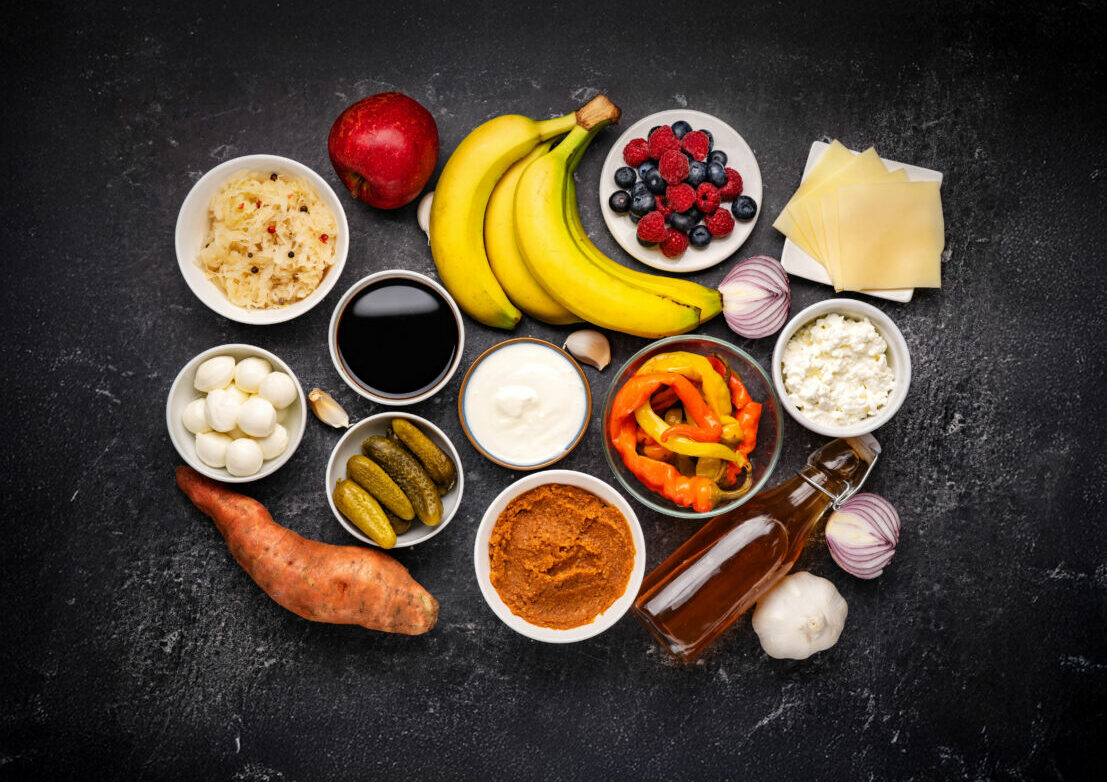 Probiotic and prebiotic foods including pickles, vegetables, fermented vegetables, fruit and milk products good for immunity and the gut. Healthy diet concept. Black backround. Top view