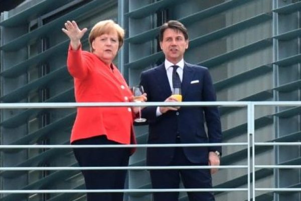 epa06819589 German Chancellor Angela Merkel (L) and Prime Minister of Italy Giuseppe Conte have a drink on a balcony of the Chancellery in Berlin, Germany, 18 June 2018. German Chancellor Angela Merkel and Prime Minister of Italy Giuseppe Conte meet for bilateral talks.  EPA/CHRISTIAN BRUNA