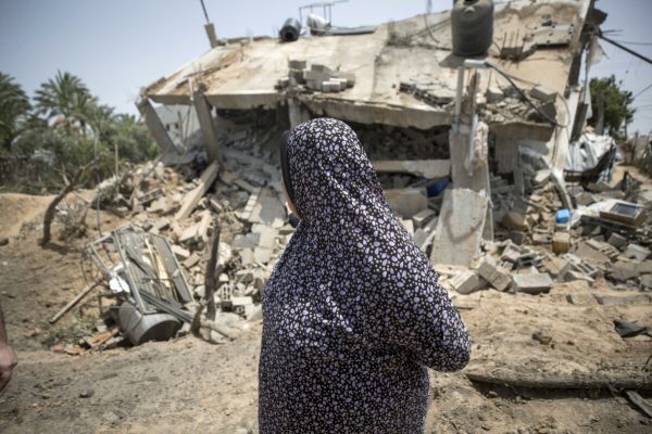 epa10622836 A woman stands in front of the destroyed house of the Abu Bashir family after Israeli air strikes in Deor A- Balah town in the central Gaza Strip, 12 May 2023. Palestinian militants in Gaza have fired rockets towards Israel, after the Israeli military carried out a series of air strikes on Islamic Jihad rocket launchers.  EPA/HAITHAM IMAD