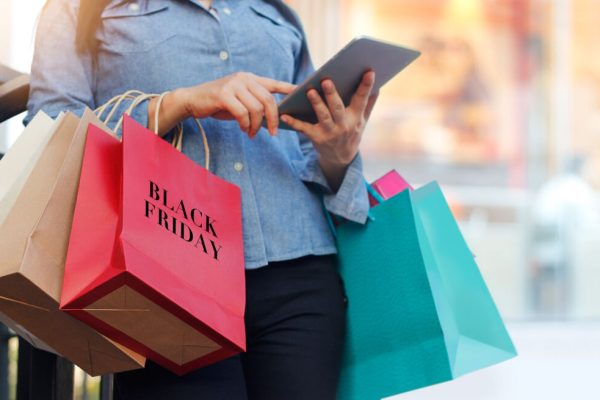 Woman,Using,Tablet,And,Holding,Black,Friday,Shopping,Bag,While