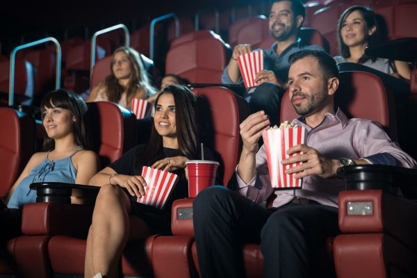 Small,Audience,Of,Young,Adults,Watching,A,Movie,And,Eating