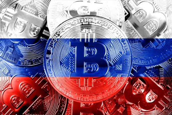 Holds,A,Physical,Version,Of,Bitcoin,And,The,Russian,Flag.