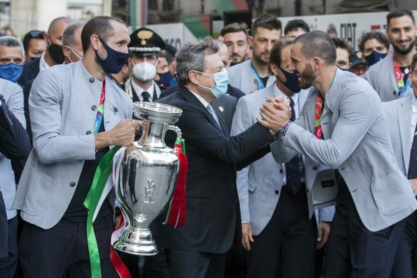 epa09340684 (L-R) Italy's captain Giorgio Chiellini, Italy's Prime Minister Mario Draghi, defender Leonardo Bonucci, and teammates pose with the UEFA EURO 2020 winner's trophy, as players of Italy's national football team arrive to attend a ceremony at the prime minister's office Palazzo Chigi in Rome, Italy, 12 July 2021. Italy won the UEFA EURO 2020 final the previous day.  EPA/ROBERTO MONALDO/LAPRESSe / POOL