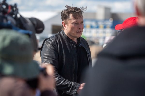 17 May 2021, Brandenburg, Grünheide: Elon Musk (l), Tesla CEO, stands on the construction site of the Tesla factory and talks to visitors. He has taken a look at the construction progress of the new factory in Grünheide near Berlin, which will probably start production several months later than originally planned. The 49-year-old did not initially comment on Monday. Photo: Christophe Gateau/dpa