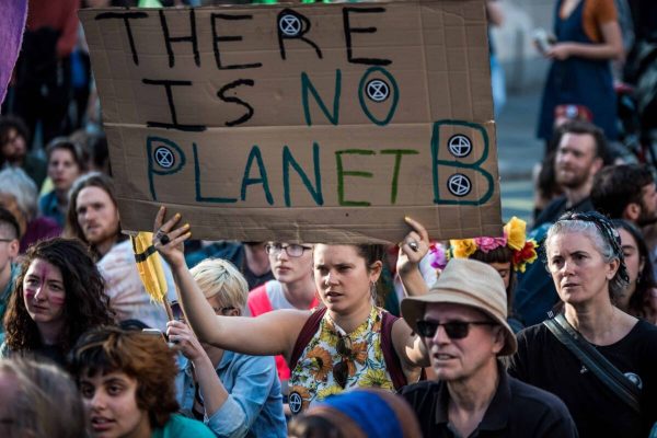 April 19, 2019 - London, United Kingdom - A woman holding a banner sitting to block the passage of the truck that was carrying the boat ''Berta Caceres'' in Oxford Street during the Extinction Rebellion Strike in London...An operation of hundreds of policeman was mobilized to remove the pink boat from Oxford Circus. .Extinction Rebellion have blocked five central London landmarks for fifth day in protest against government inaction on climate change. (Credit Image: © Brais G. Rouco/SOPA Images via ZUMA Wire)