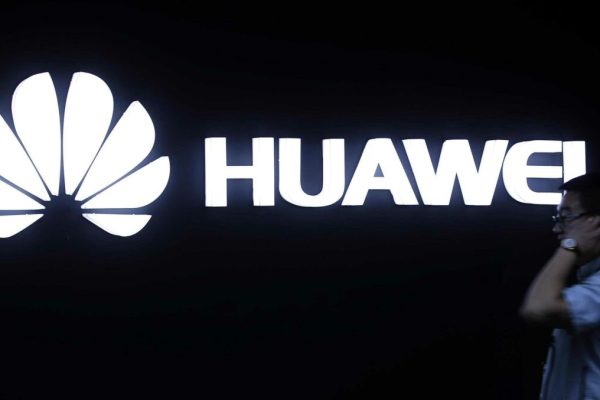 In this May 26, 2016, photo, a man walks past a Huawei logo during a launch event for the Huawei Matebook in Beijing. As trade disputes simmer, Chinese telecommunications giant Huawei, the No. 3 smartphone brand, is shifting its growth efforts toward Europe and Asia in the face of mounting obstacles in the U.S. market. (ANSA/AP Photo/Mark Schiefelbein) [CopyrightNotice: Copyright 2018 The Associated Press. All rights reserved.]