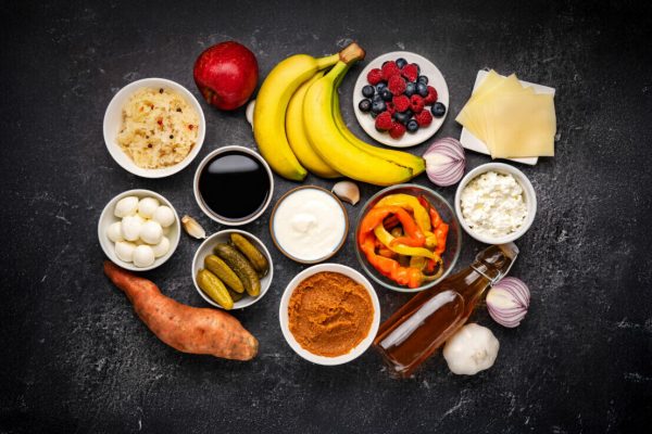 Probiotic and prebiotic foods including pickles, vegetables, fermented vegetables, fruit and milk products good for immunity and the gut. Healthy diet concept. Black backround. Top view