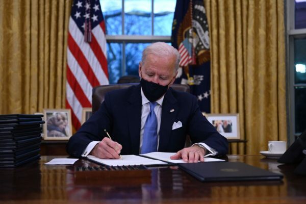 US President Joe Biden sits in the Oval Office as he signs a series of orders at the White House in Washington, DC, after being sworn in at the US Capitol on January 20, 2021. (Photo by Jim WATSON / AFP)