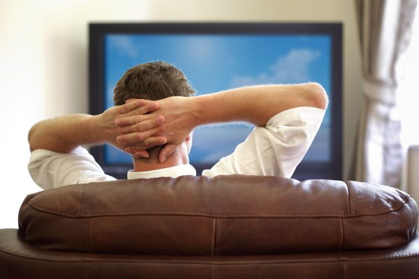 Man,Sitting,On,A,Sofa,Watching,Tv,With,Hands,Folded
