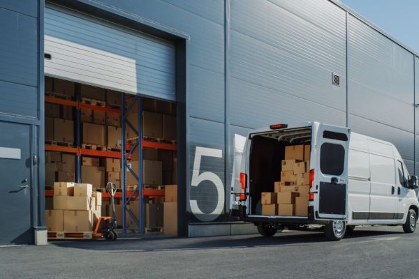 Outside,Of,Logistics,Warehouse,With,Open,Door,,Delivery,Van,Loaded