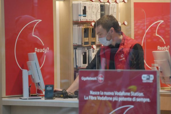 Un addetto di Vodafone con il volto coperto da una mascherina sanitaria al lavoro in un punto vendita a Milano, 03 febbraio 2021. Gli impatti del Covid sui conti di Vodafone Italia allentano la morsa e nel terzo trimestre i ricavi da servizi si attestano a 1.125 milioni di euro, in calo del 7,8% (contro un -8% del secondo trimestre). La performance del trimestre, spiega una nota, "risulta influenzata in particolare dalla riduzione del traffico roaming causata dall'impatto della pandemia sui flussi di visitatori stranieri in Italia e dalla perdurante intensità competitiva nel segmento mobile". I ricavi da servizi di rete fissa crescono dell'1,1%, pari a 307 milioni di euro. I clienti in banda larga sono circa 3 milioni, in crescita del 3,3% rispetto allo stesso trimestre dell'anno precedente (+ 96.000). I servizi in fibra di Vodafone raggiungono 24,4 milioni di famiglie e imprese, di cui 8,3 milioni di unità immobiliari attraverso la propria rete ultra broadband e la partnership con Open Fiber. ho. Mobile, il second brand di Vodafone che propone un'offerta 'essenziale' ha raggiunto i 2,4 milioni di clienti. ANSA/DANIEL DAL ZENNARO