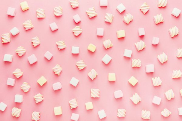 Marshmallows on pink background, flat lay or top view. Background or texture of mini marshmallows. Winter food background concept.
