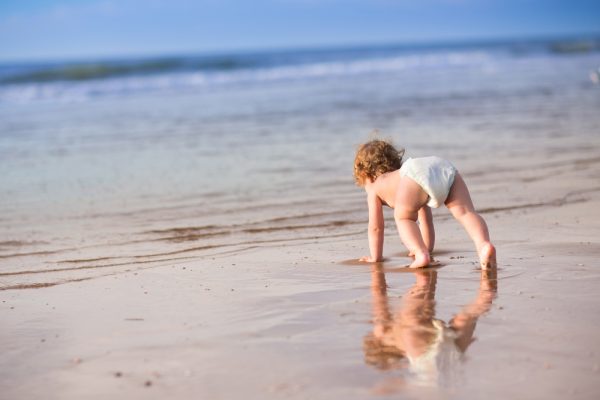 Adorable,Baby,Girl,With,Curly,Hair,Wearing,A,Diaper,Playing