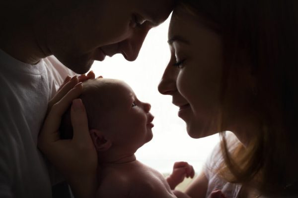 Happy,Family,With,Newborn,Baby,By,The,Window