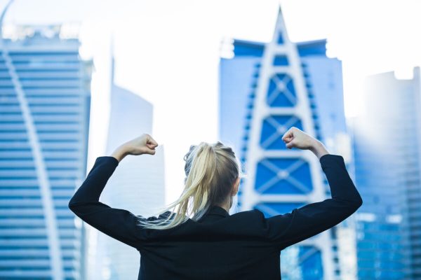 Business,Success!,Celebrating,Strong,Confident,Businesswoman,Flexing,Against,A,City