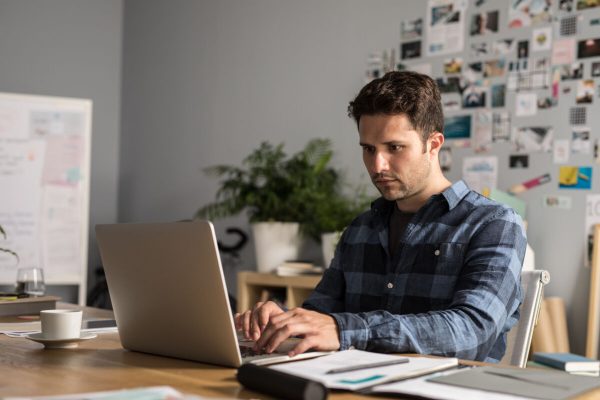 Young,Caucasian,Businessman,Sitting,At,His,Office,And,Typing,On