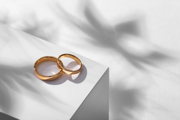 Wedding,Rings,On,A,Wooden,Box,With,Shadows,Of,Leaves