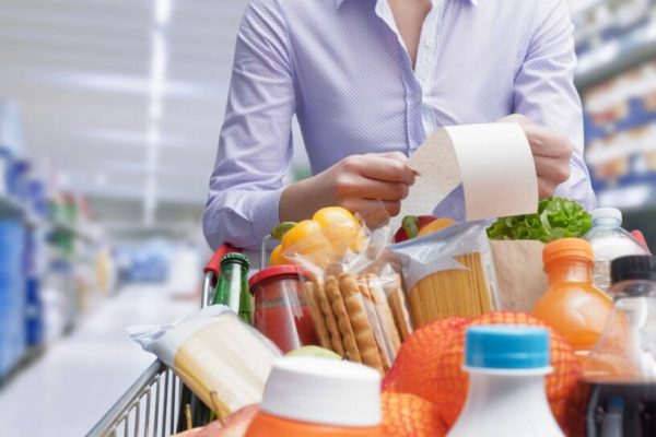 Woman,Pushing,A,Cart,And,Checking,A,Grocery,Receipt,,Grocery