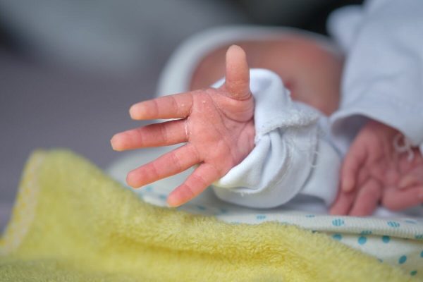 The,Newborn,Baby's,Hand,Reaches,Out,As,If,Trying,To