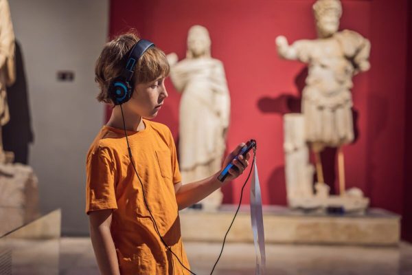 Boy,Looking,At,Sculptures,And,Listening,To,Audio,Guide,At