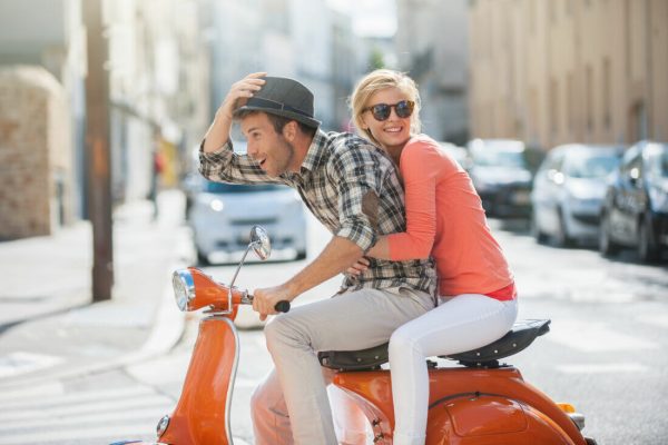 Glamorous,Young,Couple,Riding,A,Vintage,Scooter,In,The,Street,