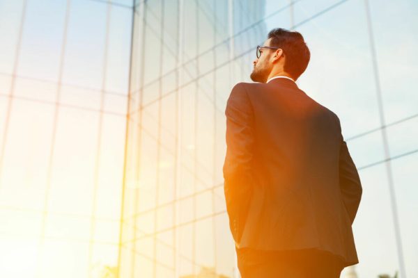 Back,View,Of,Rich,Businessman,With,Hands,In,Pockets,Looking