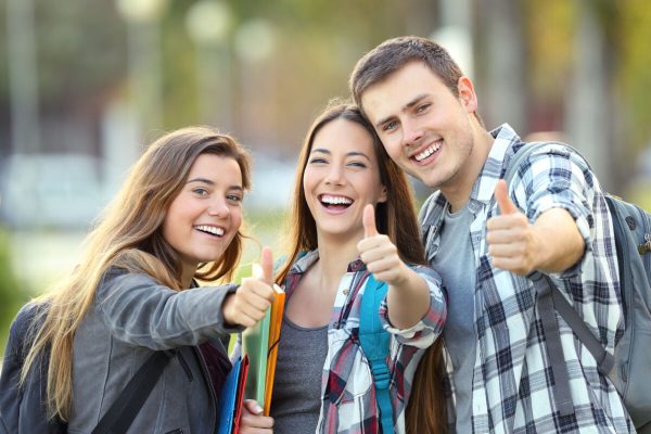 Three,Happy,Students,Looking,At,You,With,Thumbs,Up,In