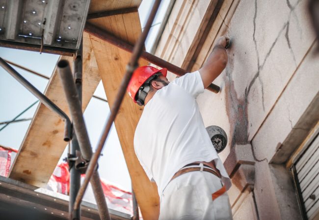 Man,Worker,Standing,On,Scaffolding,,Perform,Work,On,The,Restoration