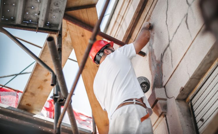 Man,Worker,Standing,On,Scaffolding,,Perform,Work,On,The,Restoration
