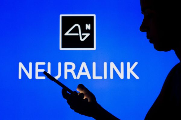 May 2, 2022, Brazil: In this photo illustration, the Neuralink logo is seen in the background of a silhouetted woman holding a mobile phone. (Credit Image: © Rafael Henrique/SOPA Images via ZUMA Press Wire)