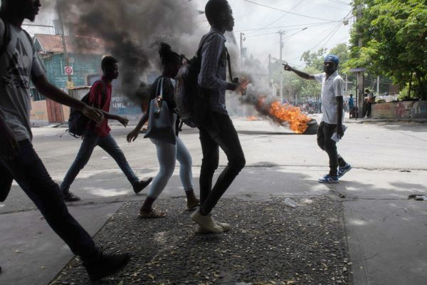 epa10800647 People walk in the middle of the street during a demonstration in Port-au-Prince, Haiti, 14 August 2023. Haitian National Police officers dispersed the demonstrators with tear gas after residents of the Carrefour-Feuilles area protested against the insecurity they suffer due to the action of armed gangs.  EPA/Johnson Sabin